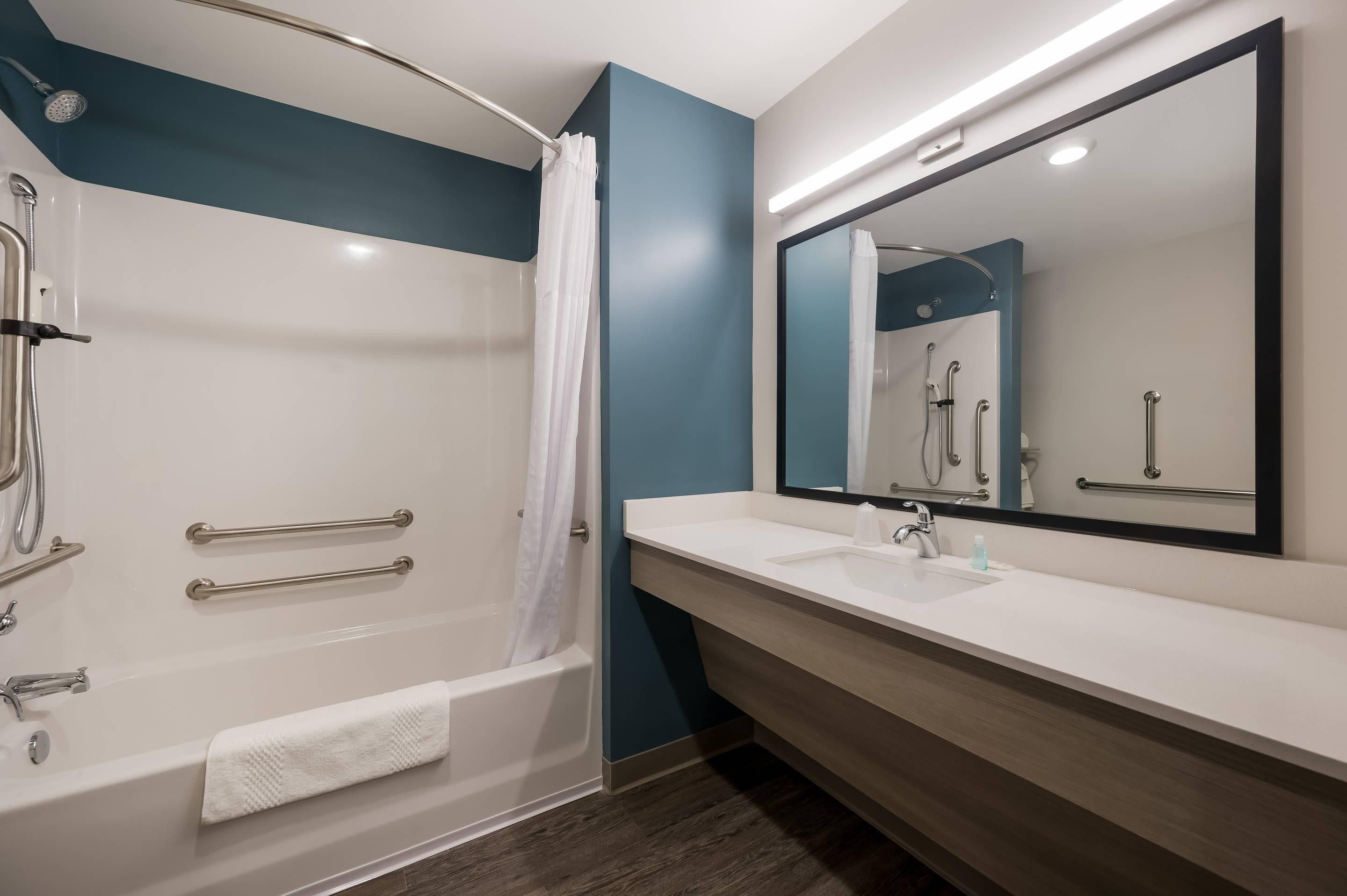 A modern bathroom with a bathtub, shower, and vanity.