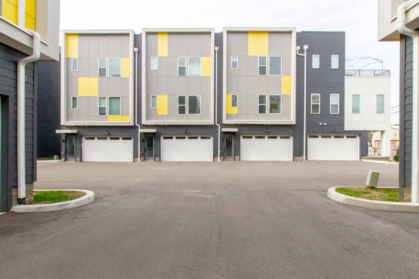Une rangée d’immeubles résidentiels modernes à plusieurs étages, dotés de portes de garage.