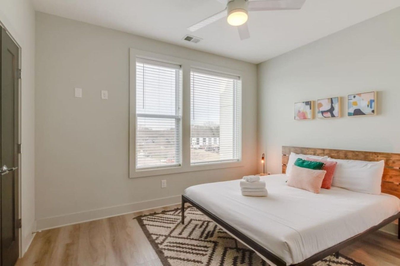 A bedroom with a bed, a ceiling fan, a window with blinds, and a rug.