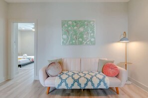 Una habitación con sofá, lámpara de pie y un cuadro en la pared.