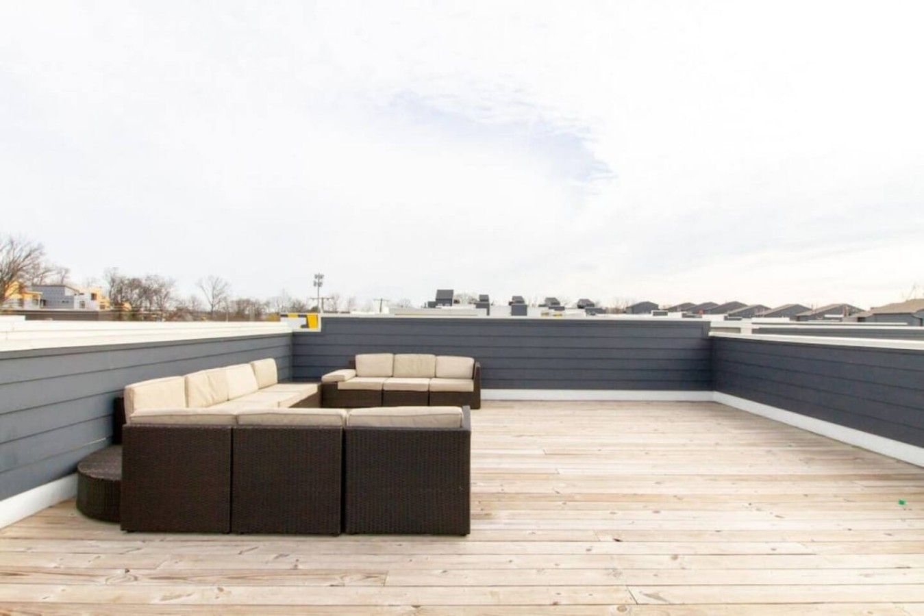 Une terrasse sur le toit avec un canapé d’angle aux couleurs sombres et une petite table ronde.