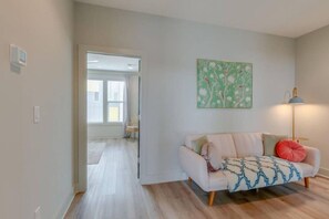 Ein Wohnzimmer mit einer Couch, einer Lampe und einem Gemälde an der Wand.