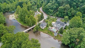 Vista aérea de una zona residencial con un río, un puente y casas con jardines y comodidades al aire libre.