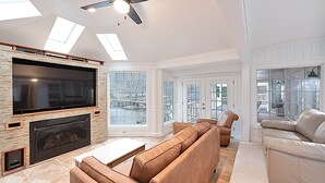 Amplia sala de estar con una televisión de pantalla plana grande, chimenea, sofá modular y ventilador de techo.
