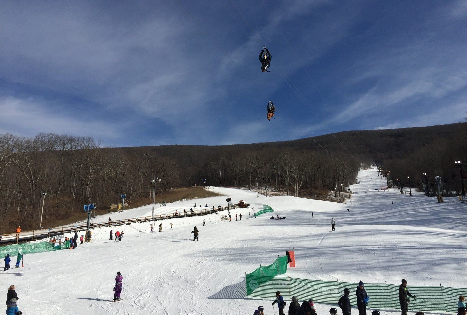 Pista de esqui coberta de neve, com esquiadores e snowboarders.