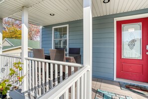 A porch with a white railing, a red door, and a window. - Beach Haven | Walk to Downtown Chincoteague, Wraparound Deck, Smart TVs & Garage for Beach Gear (Chincoteague Island)