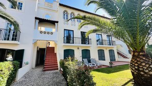 A two-story building with a central staircase, multiple balconies, and a well-maintained garden with palm trees. - Charming 2 bedroom triplex in the Old Village, Vilamoura, Algarve (Vilamoura)