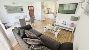 A modern living room with a grey sofa, a coffee table, and a TV on a white stand. - Charming 2 bedroom triplex in the Old Village, Vilamoura, Algarve (Vilamoura)