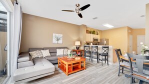 A modern living room with a sofa, coffee table, and dining area. - 1Pool Home Water Park Disney 2 m Universal Sea World! By Mystic Dunes golf ! (Kissimmee)