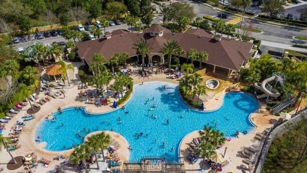 An aerial view of a resort with a large central pool, multiple lounge areas, and a parking lot. - 1Pool Home Water Park Disney 2 m Universal Sea World! By Mystic Dunes golf ! (Kissimmee)