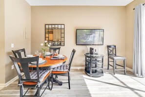 A dining area with a round table, chairs, a TV, and a bookshelf. - 1Pool Home Water Park Disney 2 m Universal Sea World! By Mystic Dunes golf ! (Kissimmee)