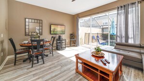 A spacious living room with a dining area, large windows, and a ceiling fan. - 1Pool Home Water Park Disney 2 m Universal Sea World! By Mystic Dunes golf ! (Kissimmee)