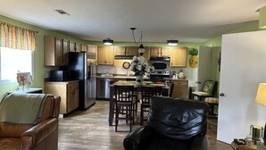 A spacious kitchen with wooden cabinets, a black refrigerator, and a dining area with a table and chairs.
