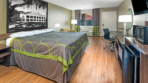 A hotel room with a large bed, a desk with a computer, a TV, and a window with curtains. - Super Place Inn (Opelousas)