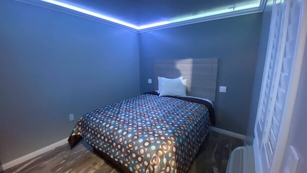 A bedroom with a patterned bedspread, a headboard, and a ceiling light. - La Perla Motel (South Gate)