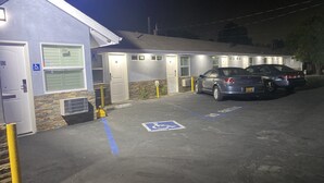 A parking area with handicapped accessible spaces, a fire hydrant, and a building with multiple doors. - La Perla Motel (South Gate)