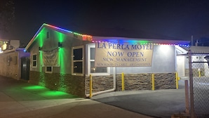 A motel with a sign indicating it's now open and new management. - La Perla Motel (South Gate)