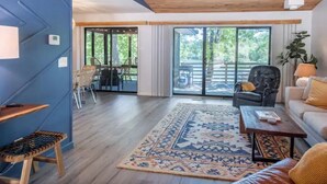 A modern living room with a wooden ceiling, a large window, and a view of the outdoors. - Lakefront AND on the MTB trails! (Bella Vista)