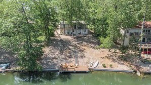 A lakeside property with a dock, a covered seating area, and a pathway leading to a house surrounded by trees. - Lakefront AND on the MTB trails! (Bella Vista)