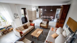 A spacious living room with a sofa, armchairs, a coffee table, and a dining area in the background. - Le Bas de Leynes - LEYNES (LEYNES)