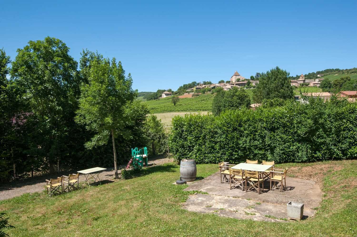 A rural outdoor setting with a picnic table and chairs, a barrel, and a playground.