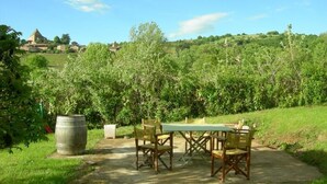 An outdoor dining area with a table and chairs, surrounded by greenery and a clear sky. - Le Bas de Leynes - LEYNES (LEYNES)