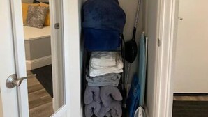 A narrow hallway with a closet containing folded clothes, a blue blanket, and a mop. - High End Guest House by I-5, Bethel, Simpson (Redding)