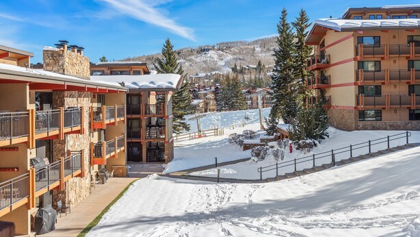 Ein mehrstöckiges Hotel mit Balkonen, im Hintergrund eine Skipiste und verschneite Flächen.