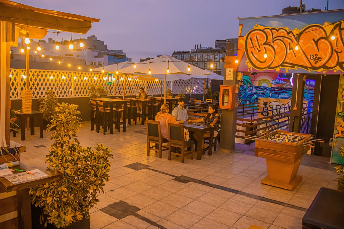 An outdoor seating area with tables and chairs, string lights, and a foosball table.