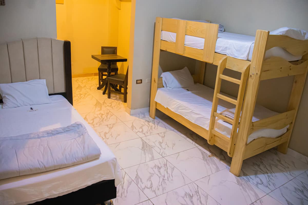 A room with two beds, a small table, and a chair.