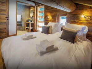 Dormitorio de cabaña de madera con una cama grande, almohadas y toallas dobladas con esmero.