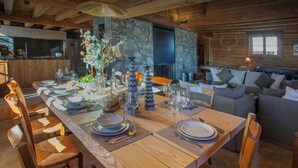 A wooden dining table set with plates, glasses, and cutlery, surrounded by woven chairs. - Chalet Sisar - ski-in ski-out break for 12, La Clusaz - OVO Network (La Clusaz)
