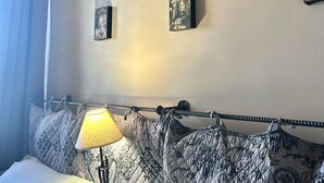 A bedroom with a bed, a bedside lamp, and a wall adorned with framed artwork. - Independent farmhouse within an organic farm, NIDO DEL GEPPIO (Lazio)