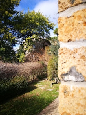 Escape to a serene garden cottage nestled among lush vegetation, with a narrow pathway leading to its rustic stone entrance.