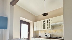 A kitchen with white cabinets, a stone countertop, and a hanging light fixture. - Independent farmhouse within an organic farm, NIDO DEL GEPPIO (Lazio)