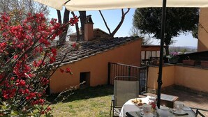 A patio with a table set for breakfast, a chair, and a table umbrella. - Independent farmhouse within an organic farm, NIDO DEL GEPPIO (Lazio)