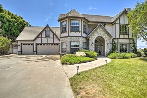 A two-story house with a stone facade, a garage, and a well-maintained lawn.