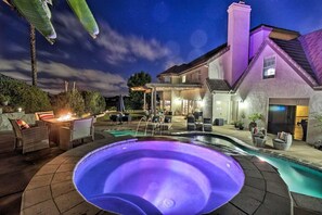 A pool area with a hot tub, outdoor seating, and a covered patio.