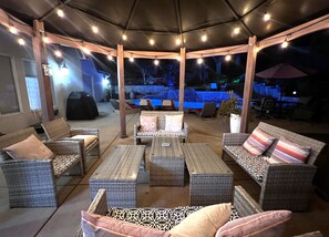 An outdoor patio area with wicker furniture, string lights, and a covered seating area.