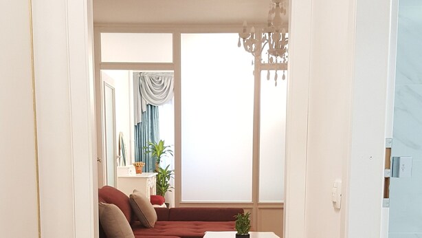 A modern living room with a wooden floor, a red sectional sofa, a white coffee table, and a chandelier.