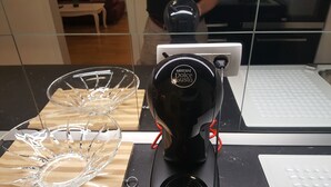 A kitchen with a coffee machine, a glass bowl, and a white countertop.