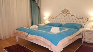 A neatly made bed with blue and peach bedding, two bedside lamps, and a decorative headboard.