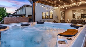 A hot tub area with seating, a covered patio, and string lights. - Paradise Retreat 94 & 96 | Neighboring Homes, Kid Friendly w/ Hot Tub's, Private Pool, Game Stations (Santa Clara)