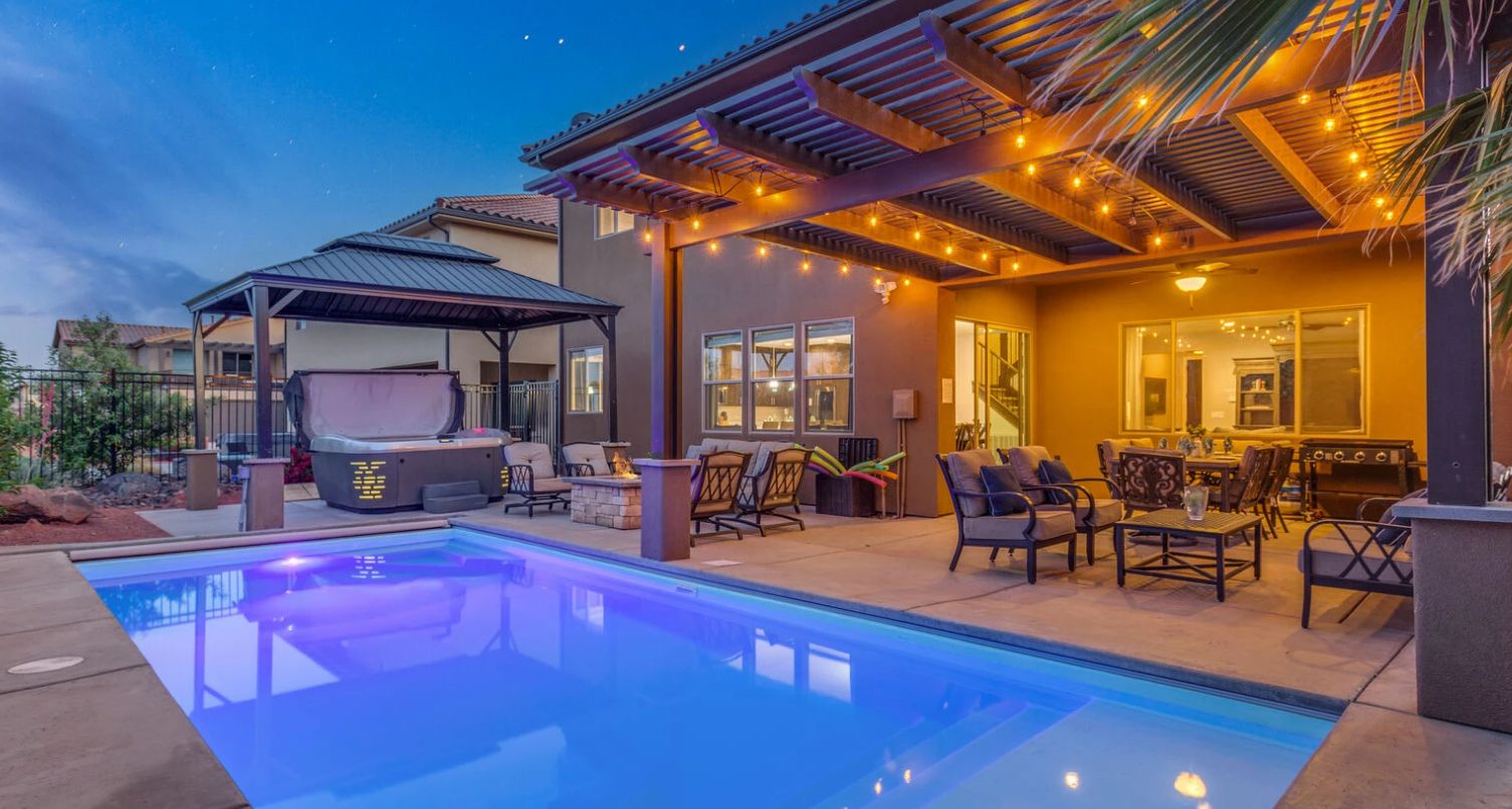 A pool area with a hot tub, outdoor seating, and a covered patio.