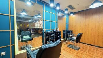 A salon interior with mirrored walls, multiple chairs, and a wooden floor.