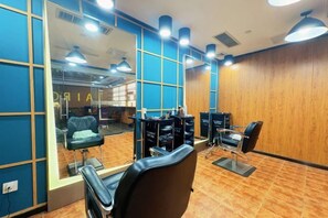 Un salón interior con paredes espejadas, varias sillas y suelo de madera.