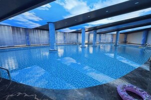 Una piscina interior con suelo de baldosas y una vista despejada del cielo a través del techo.
