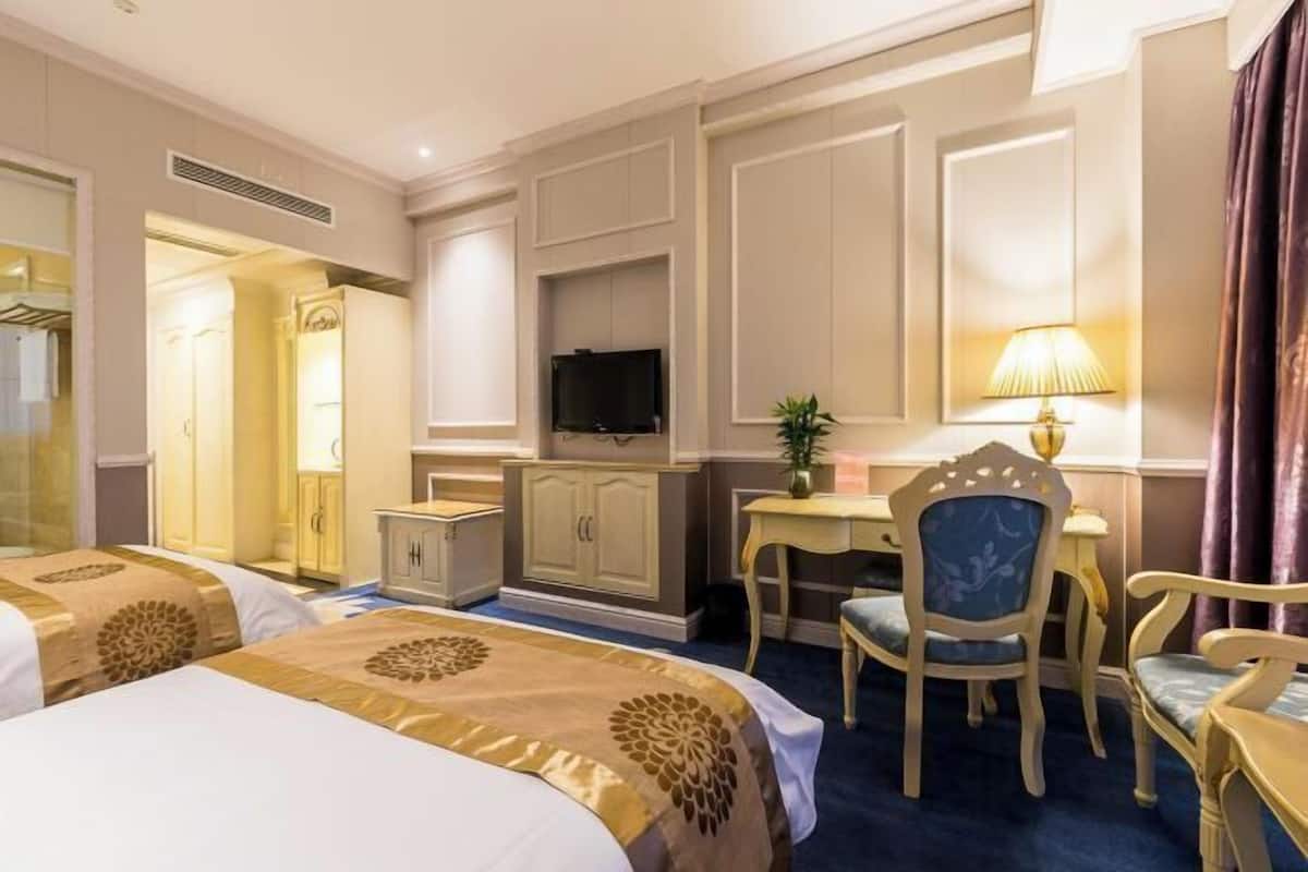 Una habitación de hotel con dos camas, un escritorio, un televisor y una silla.