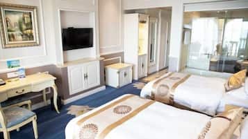 Een hotelkamer met twee bedden, een bureau, een stoel, een televisie en een groot raam.