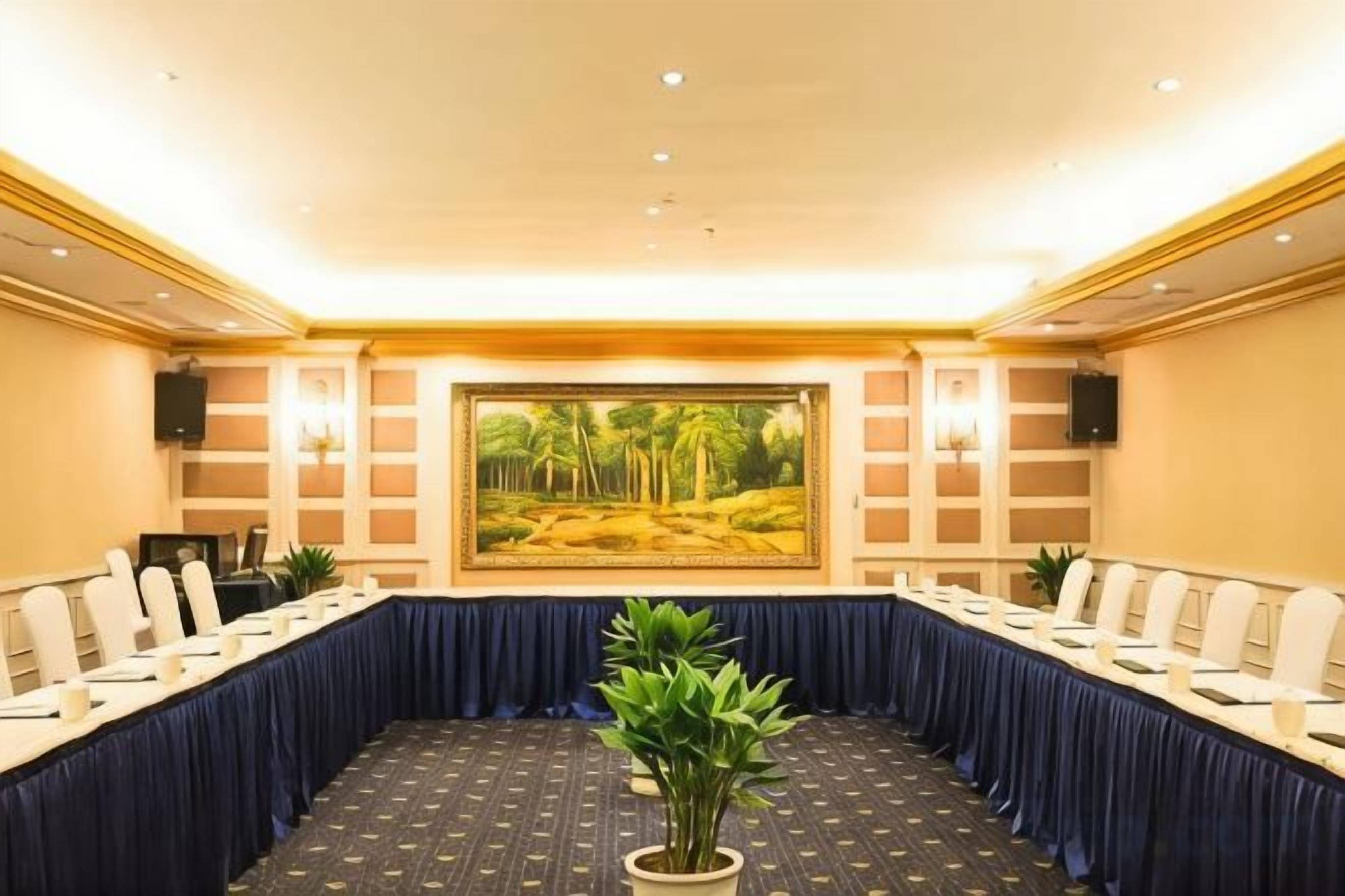A conference room with a long table, chairs, and a large painting on the wall.
